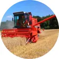 Kulatý jedlý obrázek na dort – Kombajn, červený stroj na poli u lesa (červená, žlutá, modrá)