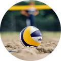 Kulatý jedlý obrázek na dort – Beach volejbal, míč v písku před sítí (žlutá, modrá, hnědá)