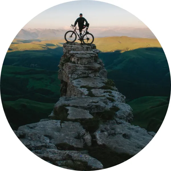Kulatý jedlý obrázek na dort – Cyklista, na vrcholu skalního útesu (šedá, zelená, hnědá)