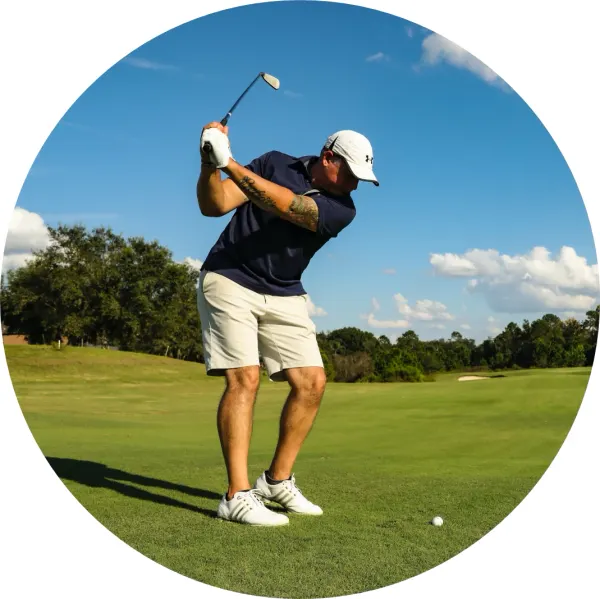 Kulatý jedlý obrázek na dort – Golf, hráč v nápřahu s míčkem na greenu (zelená, modrá, bílá)